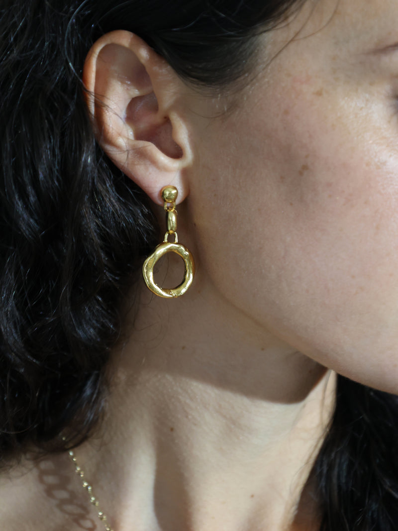 A closeup of a model's ear wearing the Ortus drop earrings in gold vermeil by Bexon Jewelry