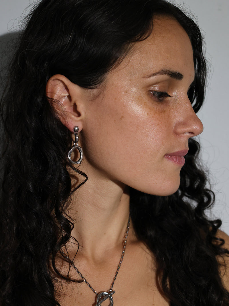 A model wears the Ortus earrings in recycled sterling silver by Bexon Jewelry