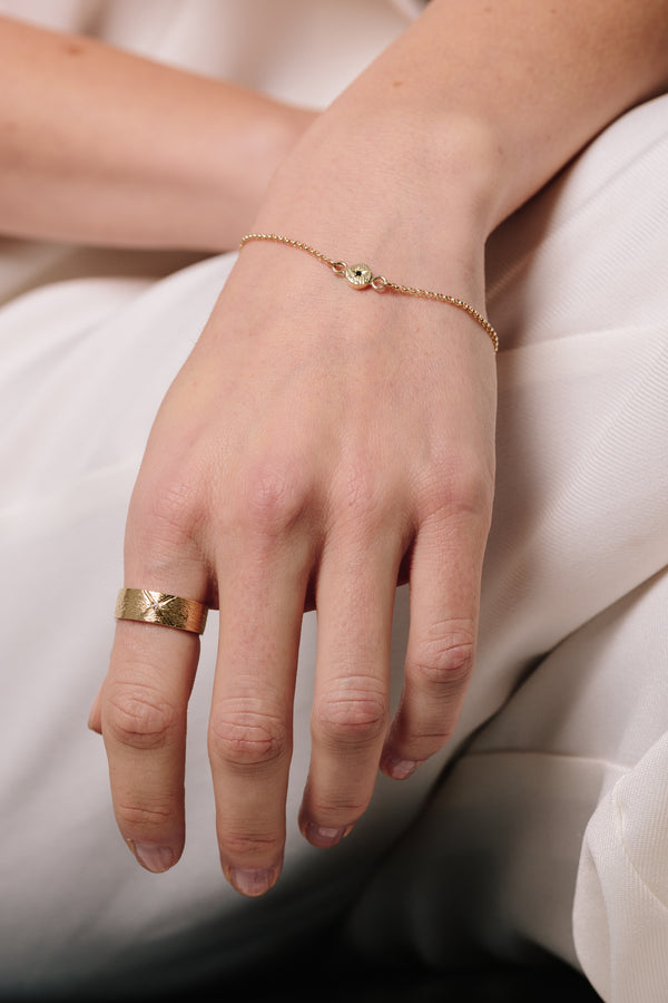 A model wears Bexon Fine Jewelry Regni wide cigar band ring in 14k recycled gold and flush set grey or black conflict-free diamond