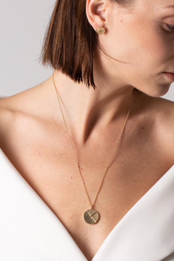 A model wears Bexon Fine Jewelry Sole Medallion pendant necklace, 20 mm. diameter on 20" rolo chain, 14k recycled yellow gold and conflict free black or grey diamonds