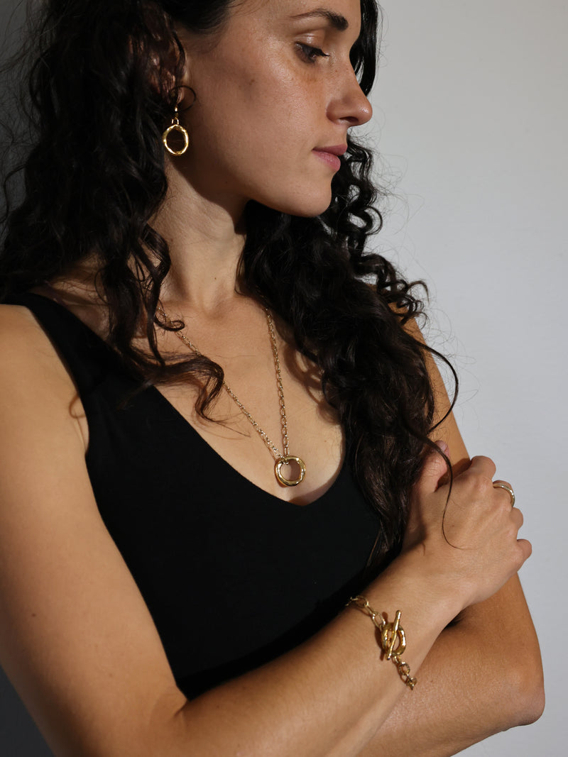 A model wears the Motus Necklace and drop earrings and bracelet in gold vermeil by Bexon Jewelry
