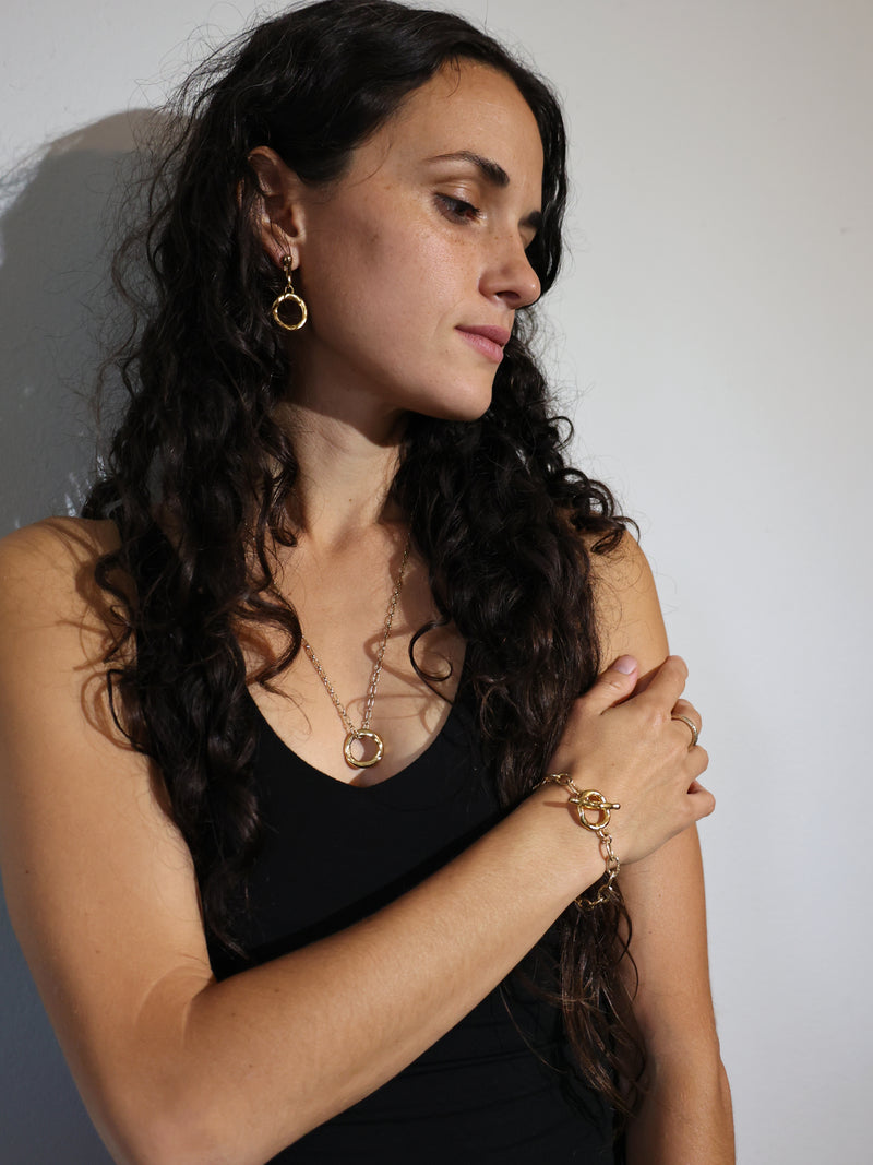 A model wears the Ortus Earrings and bracelet and necklace in gold vermeil by Bexon Jewelry