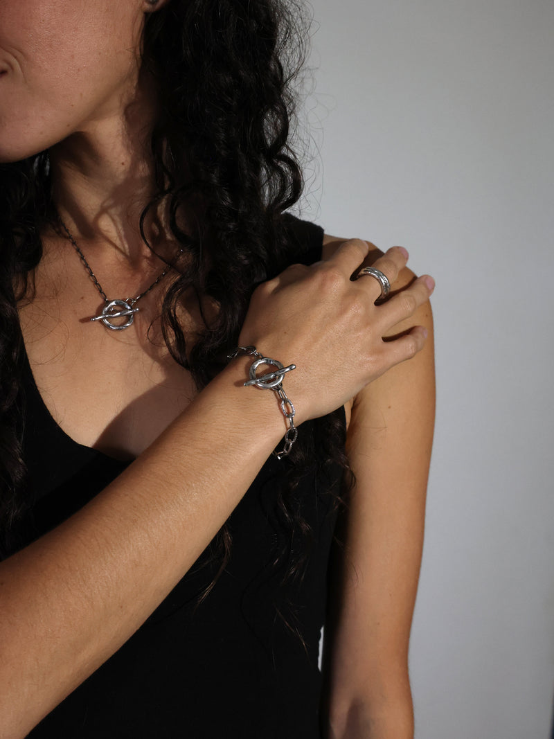 A model wearing the Vires toggle bracelet, rings, and a necklce in Sterling Silver by Bexon Jewelry