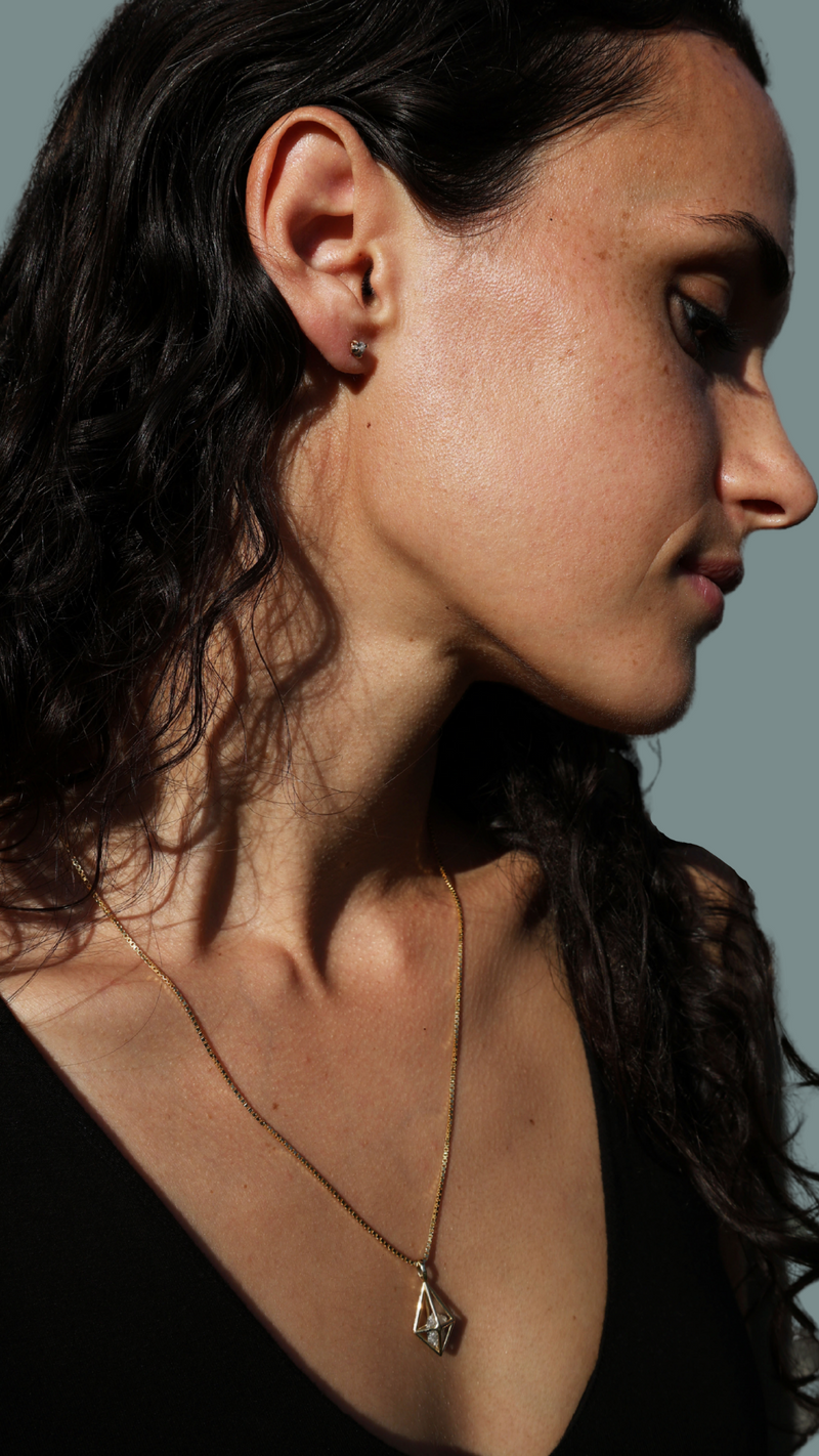 A model wears a 14k gold necklace with a rough diamond by Bexon Jewelry