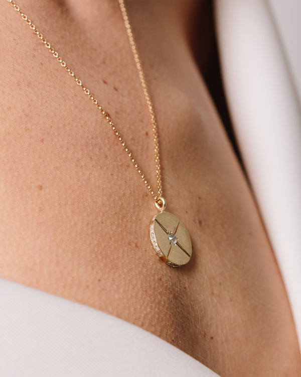 A model wears Bexon Fine Jewelry Sole Medallion pendant necklace, 20 mm. diameter on 20" rolo chain, 14k recycled yellow gold and conflict free grey pavé set diamonds and a center set 3 mm. grey rose cut diamond